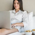 attractive-young-woman-sitting-bed-using-laptop